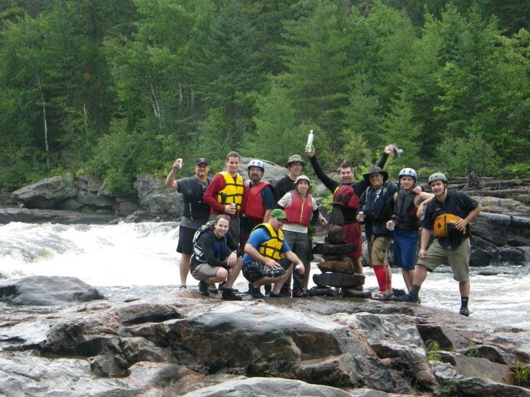 Paddlers standing in front of a rapid taking a group picture