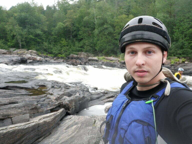 Paddler taking a selfie in front of a whitewater rapid