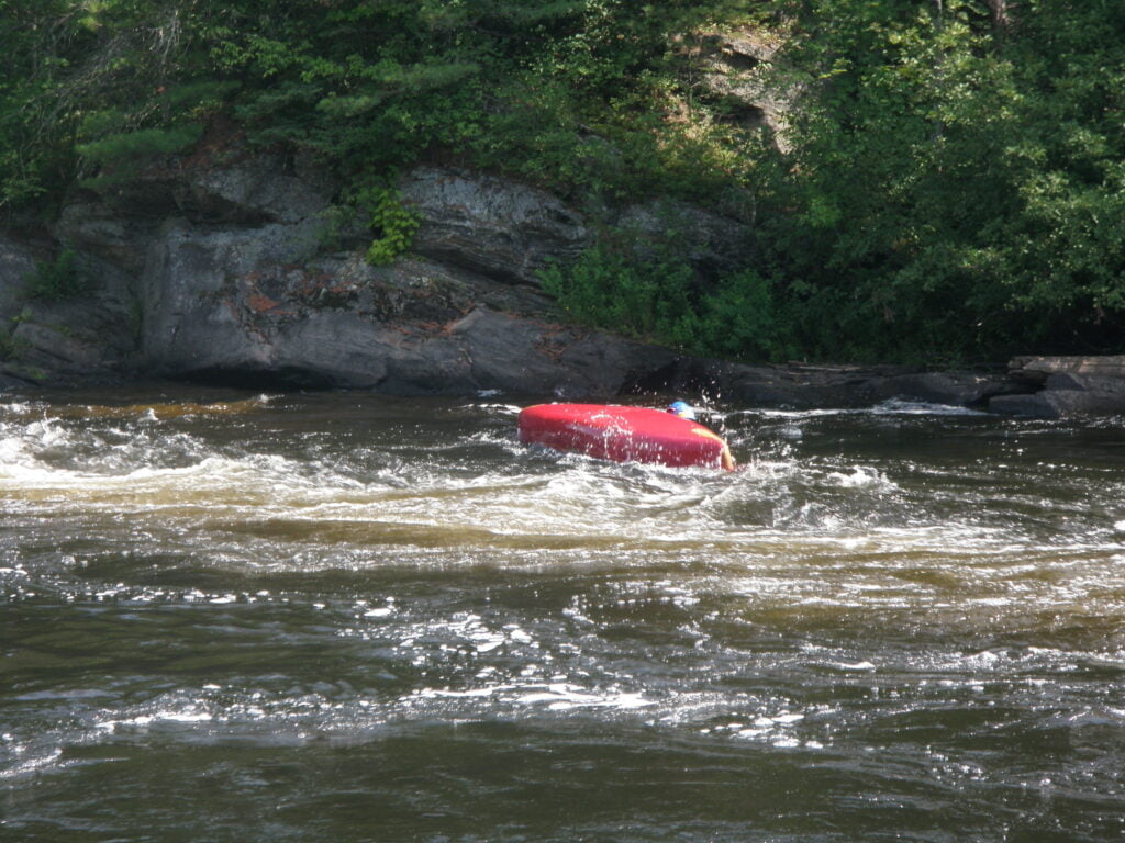 Capsized red canoe after rapid