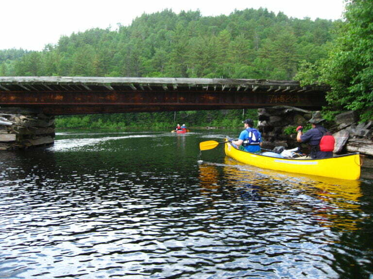 Canoe about to float under bridge with little clearance room