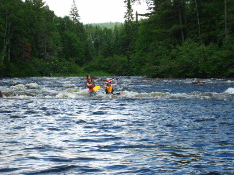 Canoe almost submerged finishing a whitewater rapid