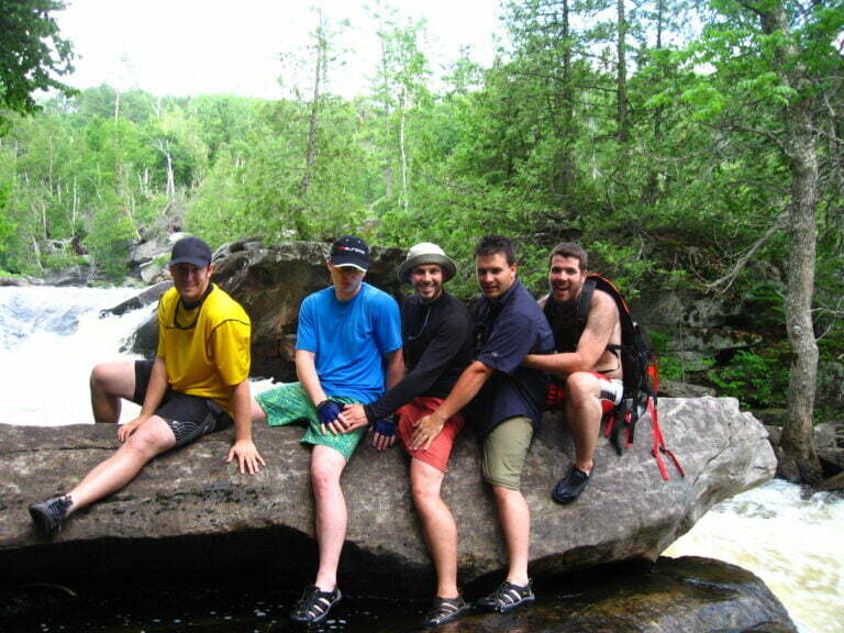 group sitting on a rock in front of waterfall