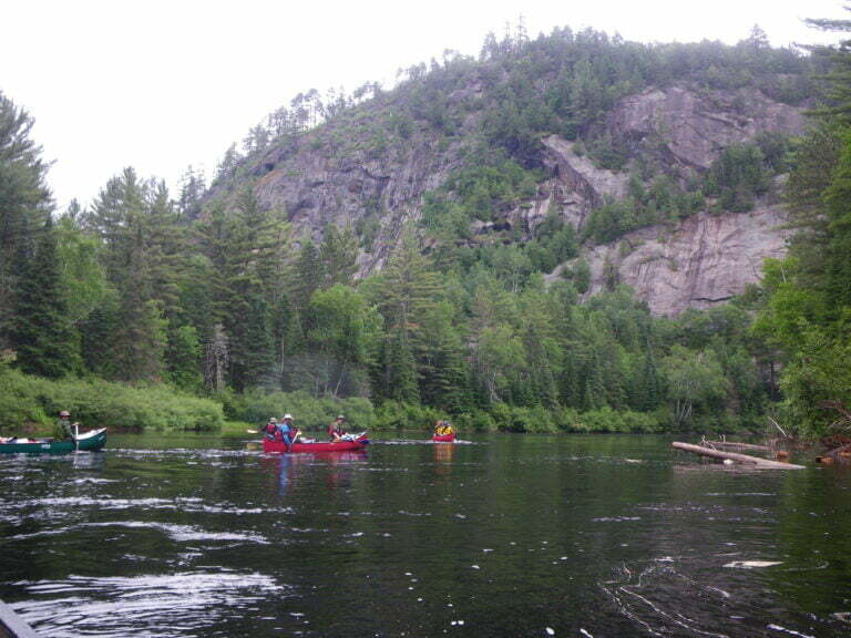 Cliff face on Dumoine river with canoes approaching it