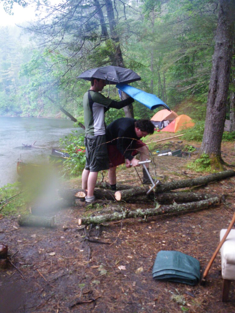 attempting to keep wood and wood cutter dry with umbrella and blue matt
